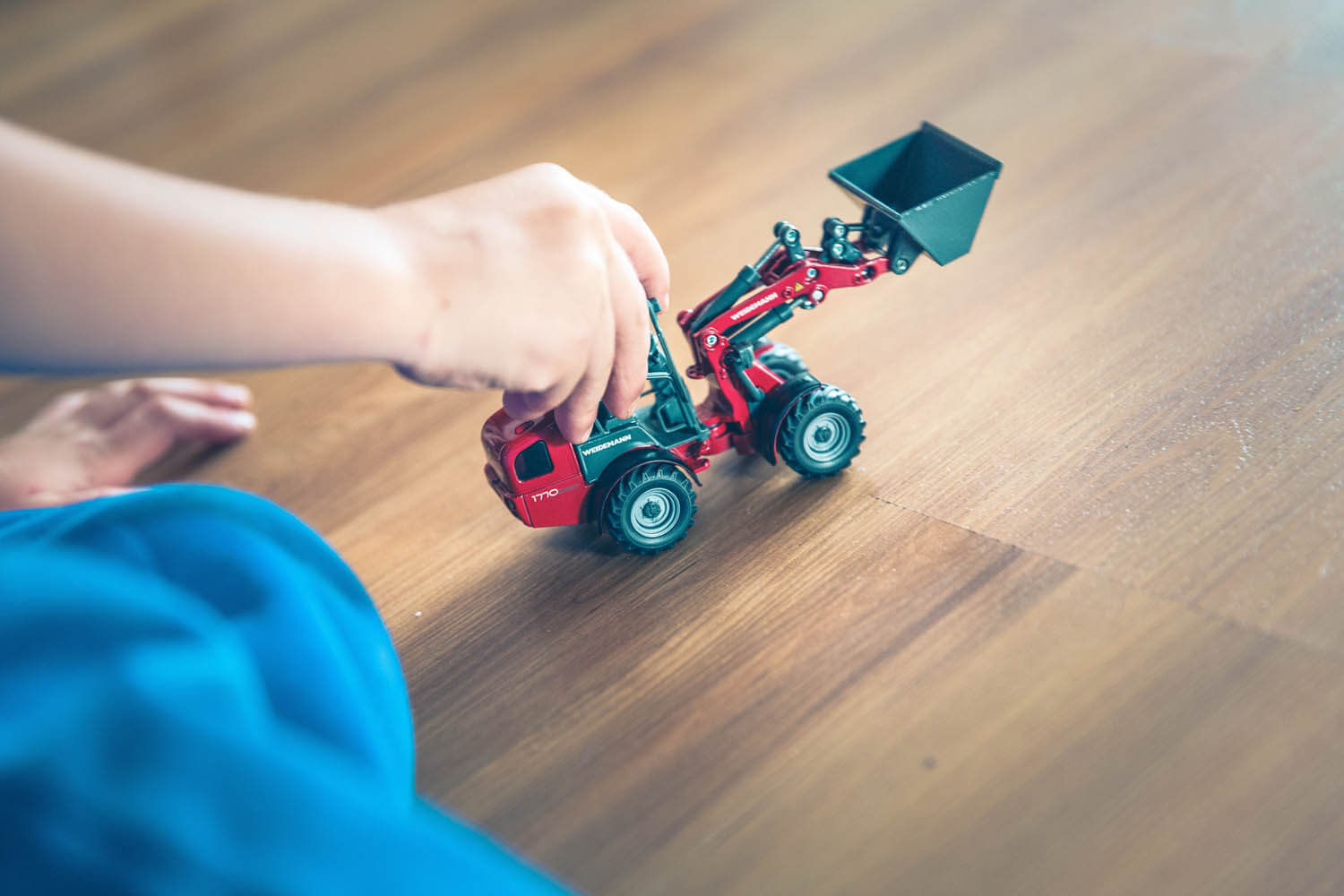 closeup of child playing with toy tractor