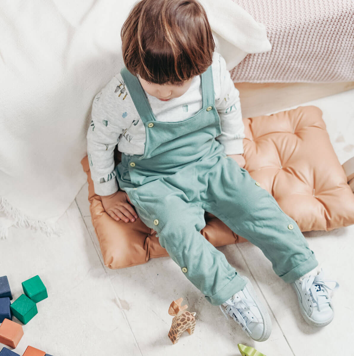 Little boy sitting on a pillow playing with toys